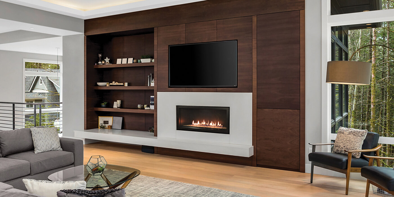 A contemporary living space with a Direct Vent linear gas fireplace installed in a custom entertainment center underneath a flat-screen TV. 